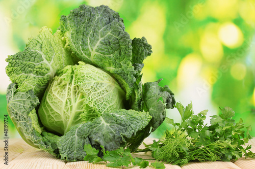 Photo: Fresh savoy cabbage on wooden table on natural background Fresh savoy cabbage on wooden table on natural background