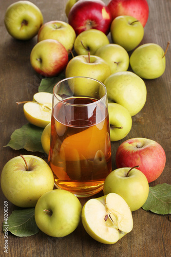 Photo: Useful apple juice with apples around on wooden table Useful apple juice with apples around on wooden table