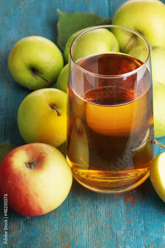 Photo: Useful apple juice with apples around on wooden table Useful apple juice with apples around on wooden table