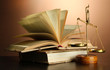 Gold scales of justice and books on brown background