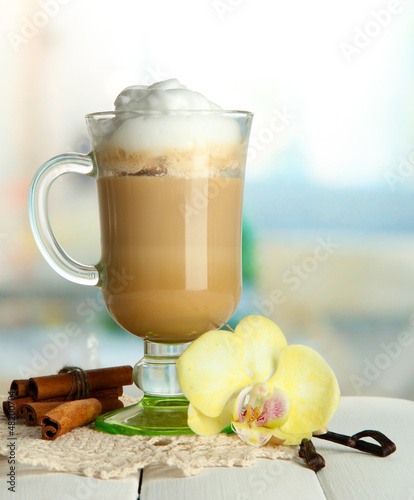 Photo: Fragrant coffee latte in glass cup with spices, on wooden table Fragrant coffee latte in glass cup with spices, on wooden table