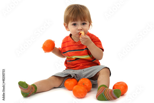 Photo: cute little boy eating tangerines, isolated on white cute little boy eating tangerines, isolated on white