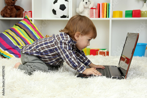 Photo: cute little boy and notebook in room cute little boy and notebook in room