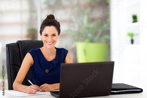 Photo: beautiful young office worker sitting by office desk beautiful young office worker sitting by office desk