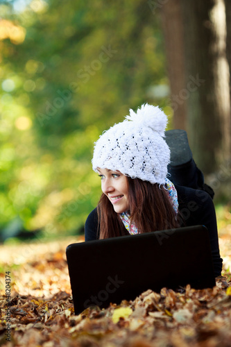 Photo: Beautiful young girl with laptop in autumn park. Young European Beautiful young girl with laptop in autumn park. Young European