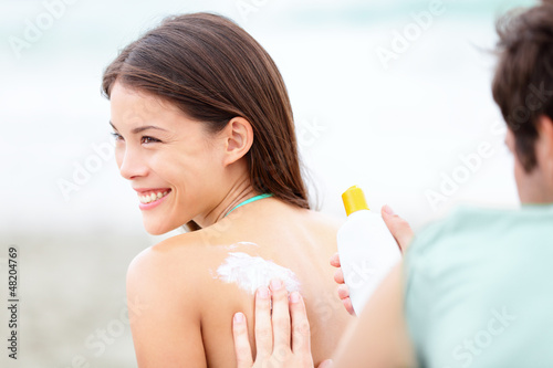 Photo: Suntan lotion / Sunscreen - young couple on beach Suntan lotion / Sunscreen - young couple on beach
