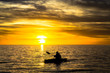 Fisherman in the kayak on the ocean in front of dramatic sunset