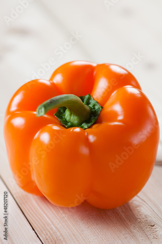 Photo: Orange bell pepper on wooden boards, studio shot Orange bell pepper on wooden boards, studio shot