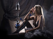 A young blond woman in erotic lingerie smoking a hookah