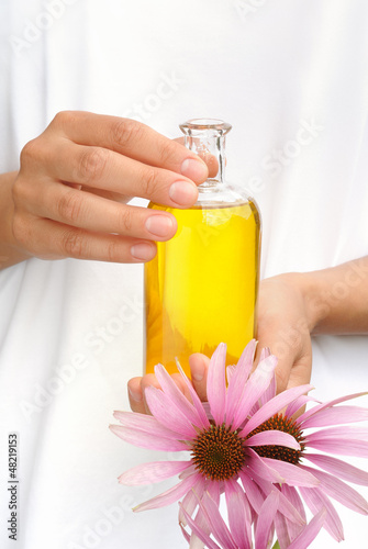 Photo: Hands of young woman holding essential oil and fresh coneflowers Hands of young woman holding essential oil and fresh coneflowers