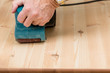 Photo: Mans hand on belt sander on pine wood Mans hand on belt sander on pine wood