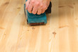 Photo: Mans hand on belt sander on pine wood Mans hand on belt sander on pine wood