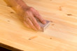 Photo: Mans hand on sanding block on pine wood Mans hand on sanding block on pine wood