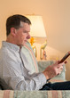 Photo: Senior man reading eBook on couch Senior man reading eBook on couch