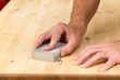 Photo: Mans hand on sanding block on pine wood Mans hand on sanding block on pine wood