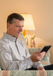 Photo: Senior man reading eBook on couch Senior man reading eBook on couch