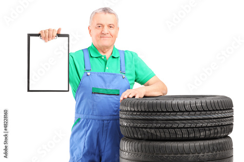 Photo: A mature worker on car tyres holding a clipboard A mature worker on car tyres holding a clipboard