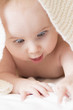beautiful baby looking out from under blanket