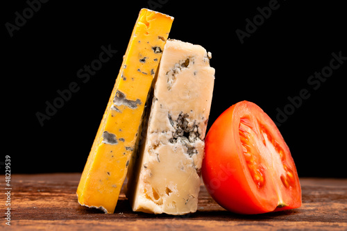Photo: Various types of cheese and tomatoes isolated on black Various types of cheese and tomatoes isolated on black