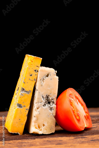 Photo: Various types of cheese and tomatoes isolated on black Various types of cheese and tomatoes isolated on black