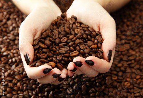 Photo: female hands with coffee beans, close up female hands with coffee beans, close up