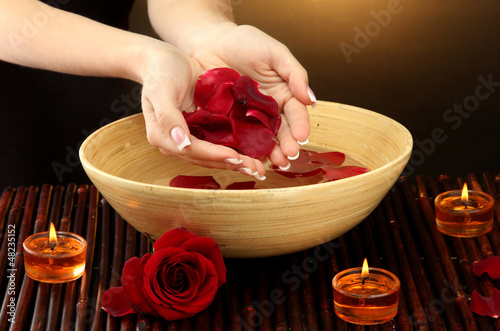 Photo: woman hands with wooden bowl of water with petals, woman hands with wooden bowl of water with petals,