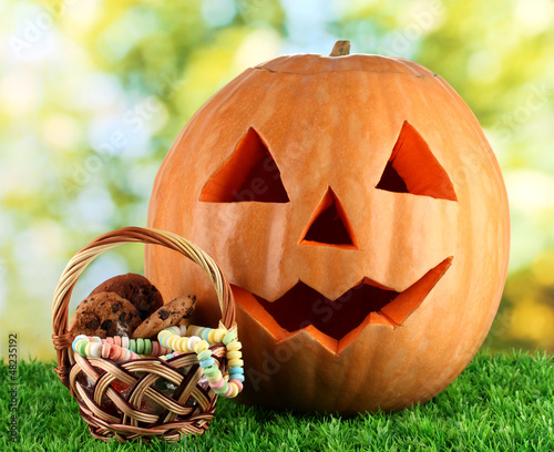 Photo: Halloween pumpkin on grass on bright background Halloween pumpkin on grass on bright background
