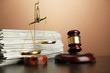 Golden scales of justice, gavel and folders on brown background