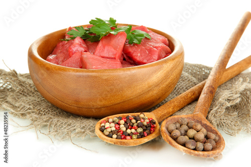Photo: Raw beef meat in bowl with herbs and spices isolated on white Raw beef meat in bowl with herbs and spices isolated on white
