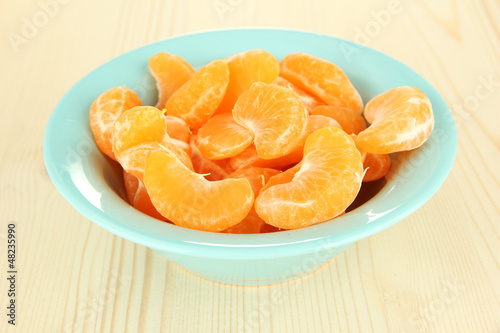 Photo: Tasty mandarine's slices in color bowl on light background Tasty mandarine's slices in color bowl on light background