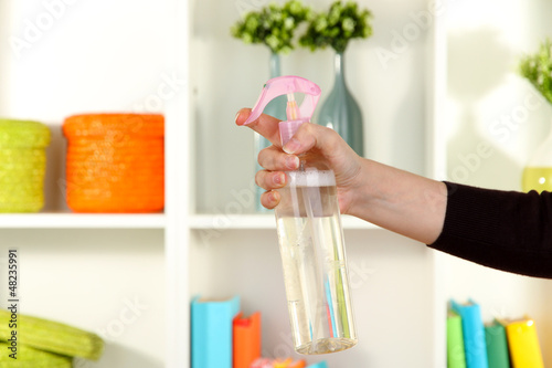 Photo: Sprayed air freshener in hand on white shelves background Sprayed air freshener in hand on white shelves background