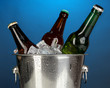 Beer bottles in ice bucket on darck blue background