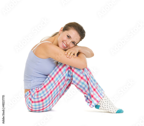 Photo: Happy young woman in pajamas sitting on floor Happy young woman in pajamas sitting on floor