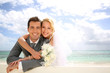 Just married couple leaning on fence by the beach