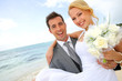 Groom holding bride in his arms at the beach