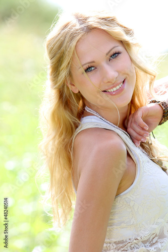 Photo: Smiling blond woman in meadow during summer Smiling blond woman in meadow during summer