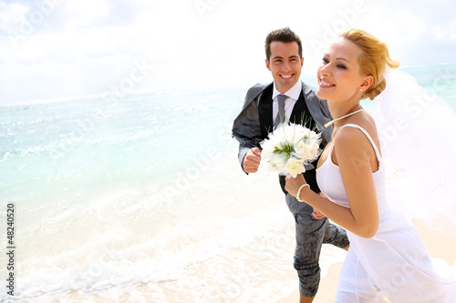 Photo: Just married couple running on a sandy beach Just married couple running on a sandy beach