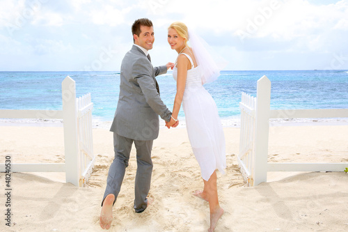 Photo: Just married couple standing by a fence towards this ocean Just married couple standing by a fence towards this ocean