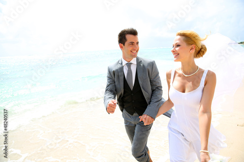 Photo: Just married couple running on a sandy beach Just married couple running on a sandy beach