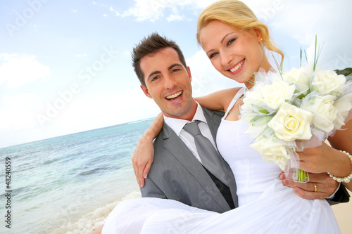 Photo: Groom holding bride in his arms at the beach Groom holding bride in his arms at the beach