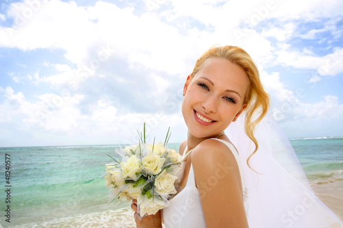 Photo: Portrait of beautiful bride standing by the beach Portrait of beautiful bride standing by the beach