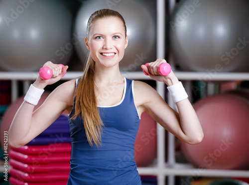 Photo: Beautiful athlete woman in sportswear working out with dumbbells Beautiful athlete woman in sportswear working out with dumbbells