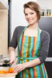 Young girl in striped apron chops vegetables