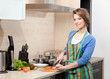 Pretty woman in striped apron cooks in the kitchen