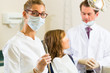 Dentist in his surgery, she holds a drill