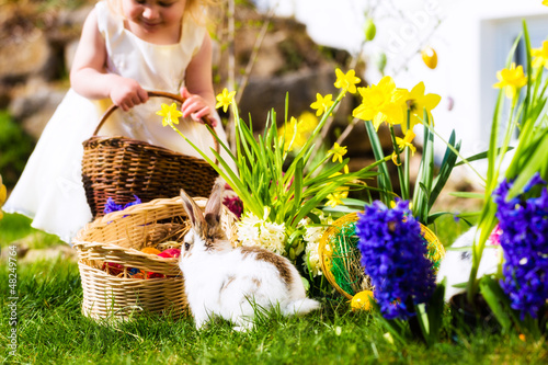Photo: Easter Bunnies on meadow with basket and eggs Easter Bunnies on meadow with basket and eggs