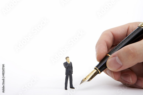 Photo: Businessman figurine looking hand holding a fountain pen Businessman figurine looking hand holding a fountain pen