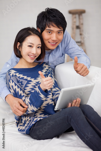 Photo: Young Asian couple using pad PC and show thumbs Young Asian couple using pad PC and show thumbs