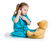 Adorable child with clothes of doctor examining teddy bear toy o