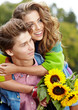 Foto: Loving young man hugging his girlfriend with sunflowers in their Loving young man hugging his girlfriend with sunflowers in their